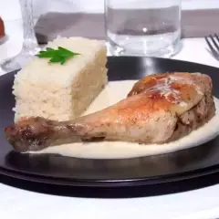 Un délicieux poulet à la crème, servi avec une portion de riz blanc et une feuille de persil. Un plat savoureux et réconfortant.