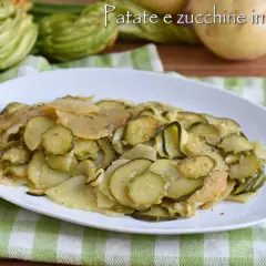 Piatto di zucchine e patate cotte in padella, con zucchine fresche e patate affettate, su un tovagliolo a quadretti verdi.