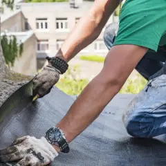 Pracownik montuje hydroizolację tarasu dwuskładnikowy szlam czy folia w płynie pod płytki.