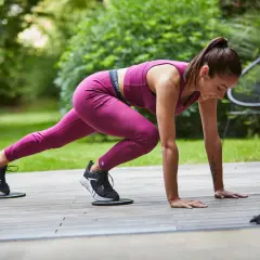 Kobieta w sportowym stroju wykonuje ćwiczenie na tarasie, poprawiając swoje VO2 max. Normy wydolnościowe są w zasięgu ręki.