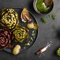 Frische Artischocken liegen bereit, um sie zuzubereiten. Mit Kräuteröl und Salz wird das Gericht zum Genuss.