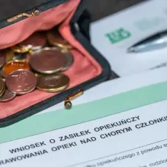 Portmonetka z monetami obok wniosku o zasiłek opiekuńczy.