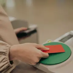 Dłoń zbliża czerwoną kartę do czytnika kart.