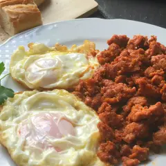 Dos huevos fritos y picadillo de chorizo, ideal para unas deliciosas recetas con picadillo de chorizo. Pan rústico al lado.