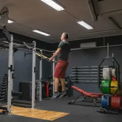 Mężczyzna wykonuje ćwiczenia plyometryczne z taśmami TRX w siłowni.
