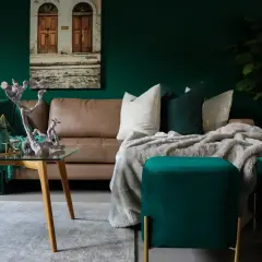 Elegancka, brązowa kanapa w salonie, otoczona zielenią i złotymi dodatkami. Inspiracje dla miłośników luksusowych wnętrz.