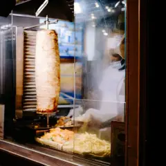 Obracający się pionowo kebab z frytkami i sałatką w witrynie.