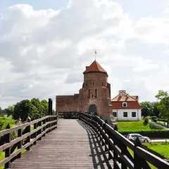 Drewniany most prowadzi do ceglanego zamku. To jedne z **ciekawych miejsc 150 km od Warszawy**, idealne na jednodniową wycieczkę.