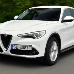 Białe Alfa Romeo Stelvio w ruchu. Kierowcy chwalą jego dynamikę, co potwierdzają liczne alfa romeo stelvio opinie.