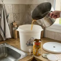 Préparation d'une bière de saison : on verse le moût d'une marmite dans un fermenteur. Une boîte de Pilsner est à côté.