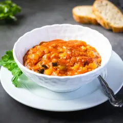 Un tazón de pisto casero, con pan tostado y perejil. ¡Cuidado, el pisto engorda si no se controla!
