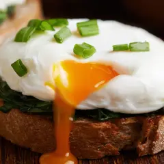 Jajko sadzone na grzance ze szpinakiem, z płynnym żółtkiem. Dwa jajka sadzone mają ok. 140 kcal.