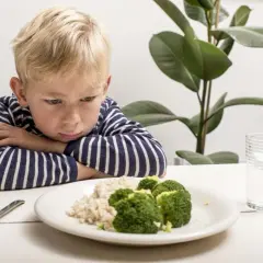 Un enfant boude devant son assiette de riz et brocolis. Une vraie galère pour trouver une idée repas enfant difficile à satisfaire !