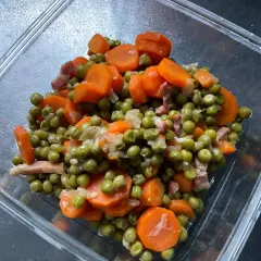 Un plat de petit pois carotte, avec des lardons, dans un récipient en verre. Un classique réconfortant.