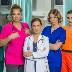 Pięć kobiet w strojach medycznych, obsada serialu "Szpital św. Anny", pozuje do zdjęcia w szpitalnym wnętrzu.