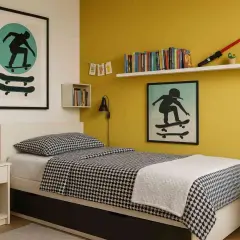 Ein cooles Jugendzimmer mit gelber jugendzimmer wandfarbe, Bett mit skateboard-Motiv und vielen Büchern.