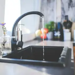 Strumień wody z kranu w kuchni. Zastanawiasz się, jak zwiększyć ciśnienie wody? Sprawdź ten poradnik!