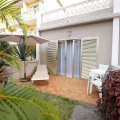 Terraza privada en el Hotel San Borondon con tumbona, sombrilla y mesa. Palmeras y vegetación exuberante rodean el espacio.
