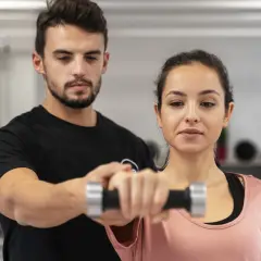 Trener pomaga kobiecie podnosić hantle podczas treningu CrossFit.