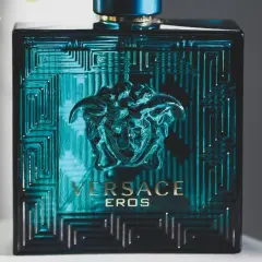 Butelka Versace Eros, symbol najlepszych perfum męskich. Intensywny, turkusowy kolor i ikoniczna głowa Meduzy.