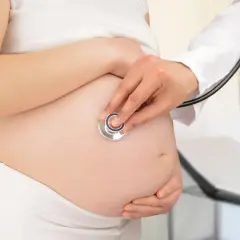 Medico ascolta battito fetale su pancia di donna incinta, controllo per gestosi gravidica.