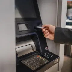 Dłoń wsuwa kartę do bankomatu PKO. Zastanawiasz się, ile można wyplacic w bankomacie PKO? Sprawdź to!