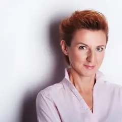 Kobieta z rudymi włosami w jasnoróżowej koszuli, uśmiecha się do obiektywu. Idealne miejsce do robienia zdjęć.