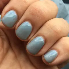En hand med ljusblå, glansig inglot nagellack.