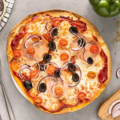 Gotowa pizza z szynką, oliwkami, pomidorkami i czerwoną cebulą na gotowym spodzie.