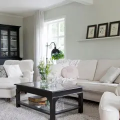 Gemütliches Wohnzimmer mit einem Sofa und Sessel in off white farbe, einem schwarzen Schrank und einem Couchtisch.