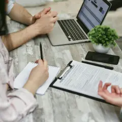 Osoby przy stole analizują dokument "Home Insurance Policy". Kobieta notuje, mężczyzna patrzy na laptopa. Może to być związane z wefox wypowiedzenie oc.