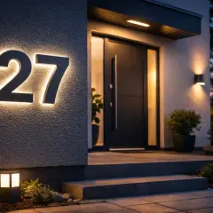 Nowoczesny **pomysł na numer domu**: podświetlane cyfry "27" na elewacji, oświetlony ganek i drzwi wejściowe.
