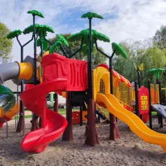 Kolorowy plac zabaw z zjeżdżalniami, drabinkami i huśtawkami na piasku.