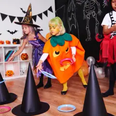 Niñas disfrutan de una divertida celebración de Halloween lanzando aros a sombreros de bruja.