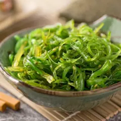 Insalata di alghe wakame in una ciotola, con bacchette. Informazioni su alga wakame controindicazioni.