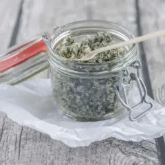 Ein Glas mit selbstgemachtem Kokos Peeling, bereit zur Anwendung. Ein kleiner Holzlöffel liegt darin.