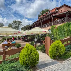 Odkryj najlepsze restauracje na Mazurach! Letni ogródek z widokiem na jezioro, gdzie można delektować się posiłkiem pod parasolami.