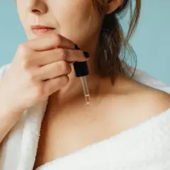 Frau trägt reines Retinol mit Pipette auf ihre Haut auf.