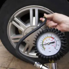 Manometro collegato a una ruota d'auto, dove è scritta la pressione dei pneumatici.