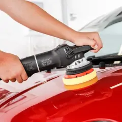 Ręce polerują czerwony lakier auta maszyną polerską. To kluczowy etap przygotowania auta do sprzedaży, by wyglądało jak nowe.