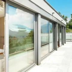 Nowoczesny balkon z przeszklonymi drzwiami i widokiem na góry.