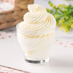 Delicioso frosting de queso cremoso, decorado en espiral, servido en un vaso de vidrio.