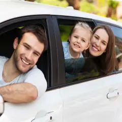 Famiglia sorridente in auto. Pensano al passaggio di proprietà tra familiari costo per un nuovo veicolo.