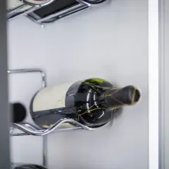 Eine Flasche Rotwein, die für die Lagerung von offenem Rotwein vorbereitet ist, liegt auf einem metallenen Gestell.