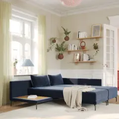 Gemütliches Wohnzimmer mit dunkelblauem Sofa, hellen Vorhängen und Regalen voller Bücher. Moderne Farben schaffen eine einladende Atmosphäre.