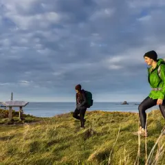 Deux randonneuses explorent le littoral breton, profitant d'une belle journée pour leur randonnée les abers Bretagne. Le ciel est couvert, mais la lumière est douce.