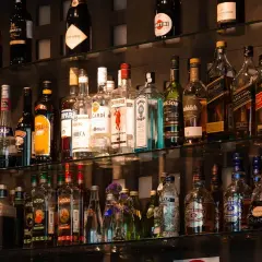 Na półkach barowych stoją butelki alkoholi, w tym kilka butelek tequili, idealnych do przygotowania pysznej margarity.