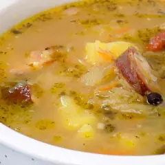 Gęsty, aromatyczny kapuśniak jak u babci, z kawałkami wędzonki, ziemniaków i marchewki, doprawiony ziołami i zielem angielskim.