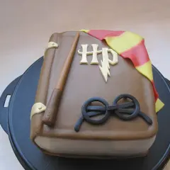 En tårta formad som en bok med Harry Potters trollstav, glasögon och Gryffindors halsduk. Ett magiskt harry potter tårta recept!