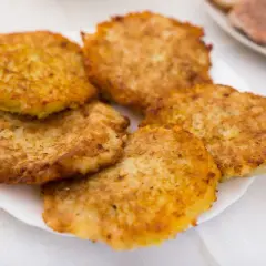 Placki ziemniaczane na białym talerzu, lekko zrumienione.
